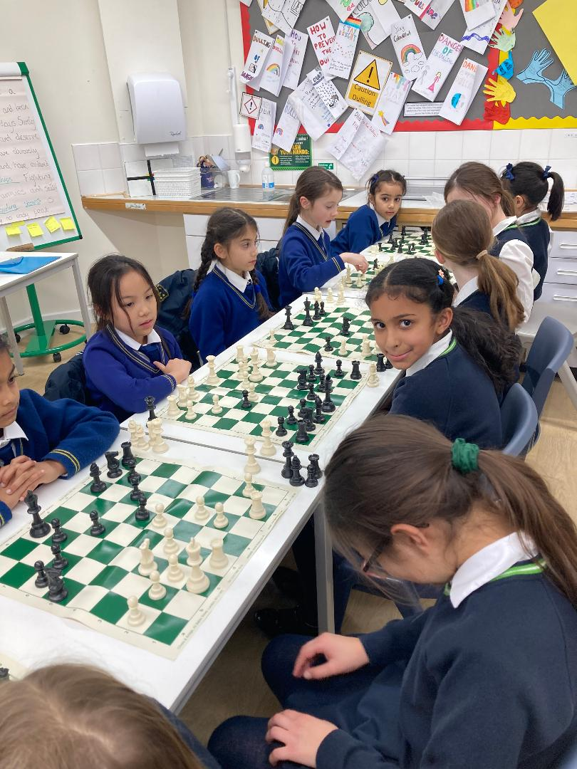 Junior School students from Wimbledon High School Juniors and Holy Cross sitting in a row playing games of chess