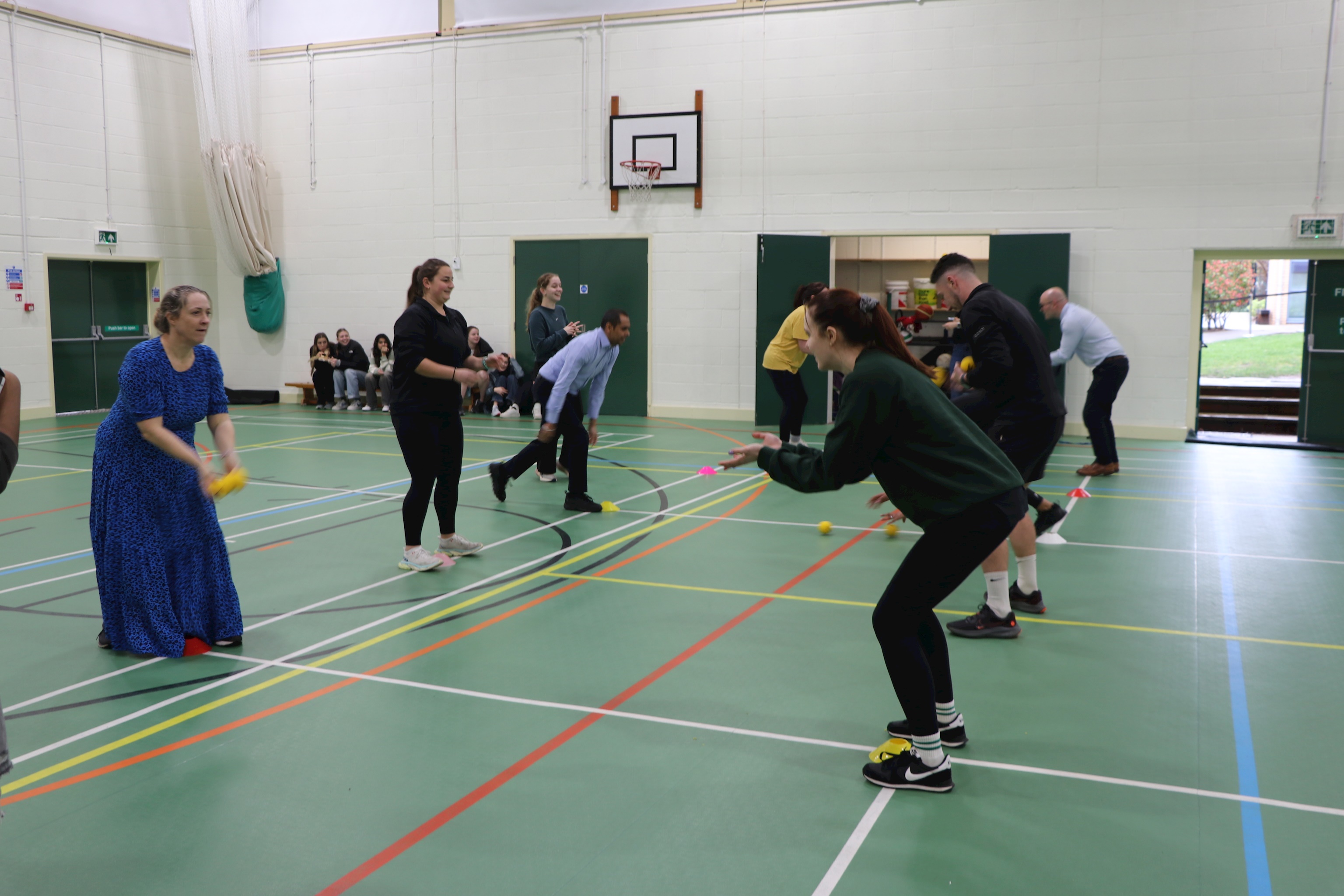 Staff members taking part in a sports science competition. They are in the sports hall playing 'catch' with a ball